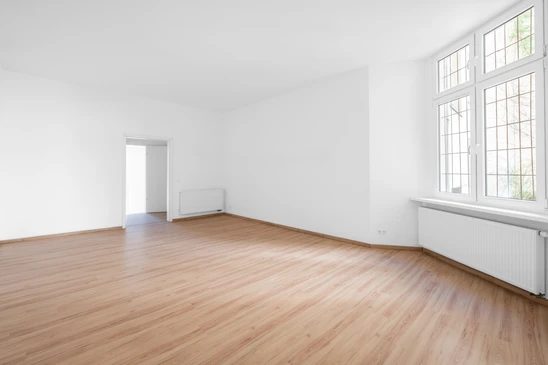 Salon moderne avec parquet en bois franc lustré, plafond blanc à moulures, colonnes structurales blanches